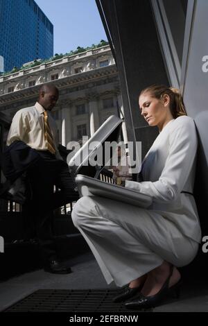 Low angle view of a businesswoman looking into a briefcase with two businessmen standing in the background Stock Photo