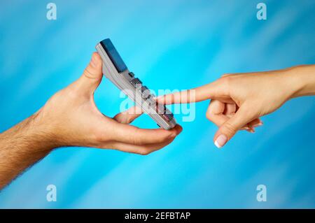 Close-up of a man holding a calculator with a womanÅ½s finger pressing a button Stock Photo