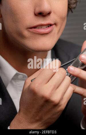 Close-up of a businessman operating a hand held device with a digitized pen Stock Photo
