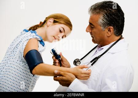 Side profile of a male doctor measuring blood pressure of a young woman