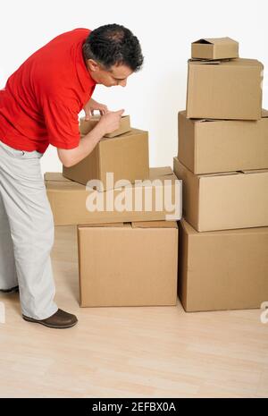 Side profile of a mid adult man packing cardboard boxes Stock Photo
