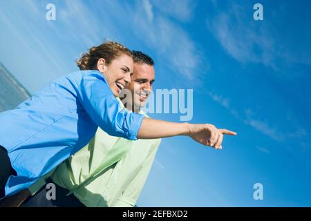 Side profile of a mid adult woman pointing with a mid adult man standing beside her Stock Photo