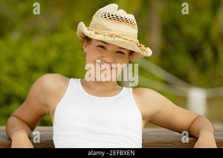 Portrait of a teenage girl posing against a wooden bench and smiling Stock Photo