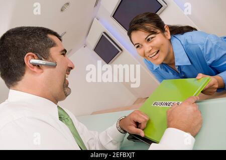 Businesswoman giving a file to a businesswoman and smiling
