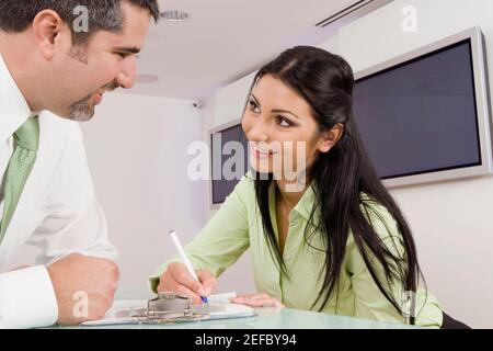 Close-up of a businessman and a receptionist looking at each other and smiling Stock Photo