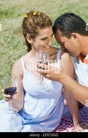 Mid adult man holding a wine glass and kissing on a mid adult womanÅ½s shoulder Stock Photo