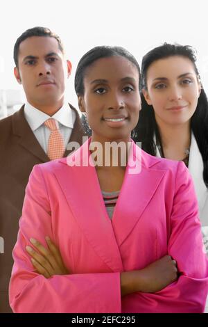 Portrait of a businesswoman smiling with two business executives standing behind her Stock Photo