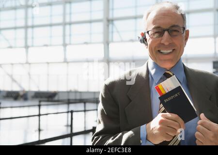 Portrait of a businessman putting a passport with an airplane ticket in his coatÅ½s pocket Stock Photo