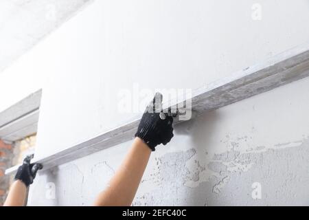 Builder Level out defects in concrete walls with cement plaster. Stock Photo