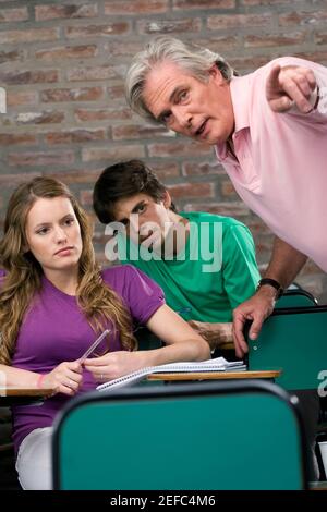 Professor assisting his students in a classroom Stock Photo