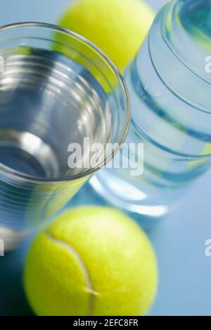High angle view of a glass of water with a water bottle and two tennis balls Stock Photo