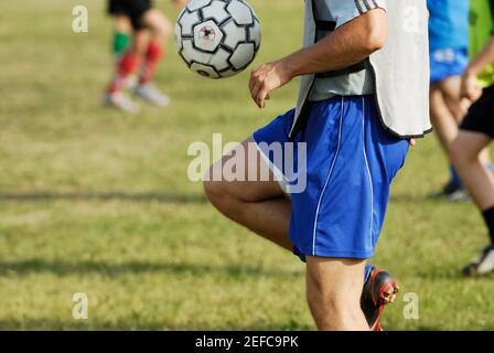 Mid section view of a soccer player balancing a soccer ball on his thighs Stock Photo