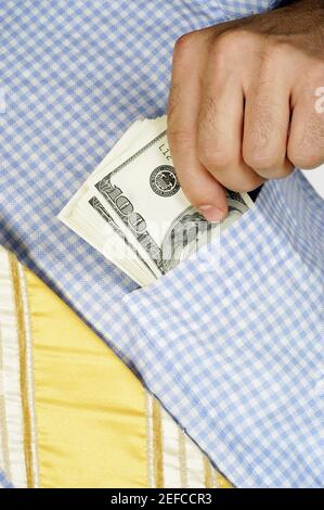 Mid section view of a businessman putting money into his shirt pocket Stock Photo