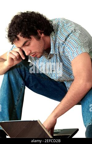 Young man talking on a mobile phone and using a laptop Stock Photo