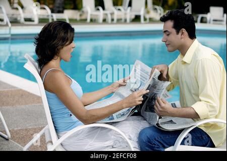 Side profile of a young couple reading a newspaper Stock Photo