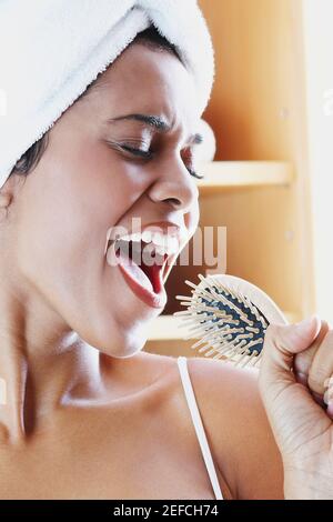 Close up of a young woman holding a hairbrush and singing Stock Photo