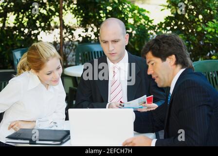 Two businessmen with a businesswoman sitting at the table Stock Photo