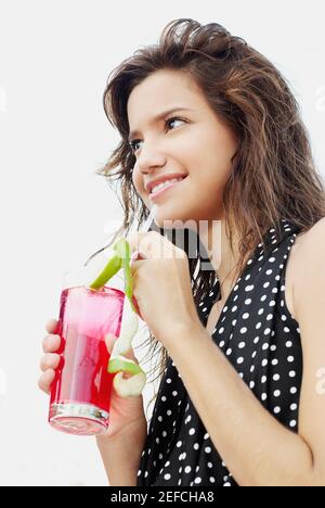 Close up of a young woman holding a glass of cocktail and smiling Stock Photo