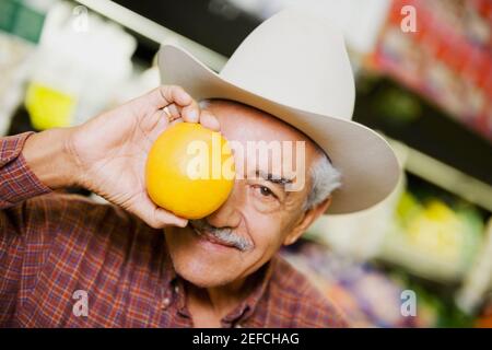 Close up of a senior man holding an orange Stock Photo