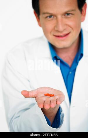 Portrait of male doctor holding pill on his palm