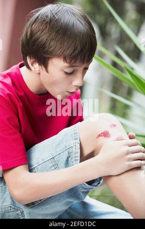 Close up of a boy holding his wounded knee Stock Photo