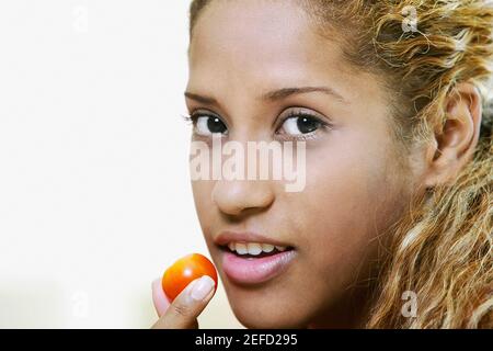 Close up of a young woman holding a cherry in front of her mouth Stock Photo