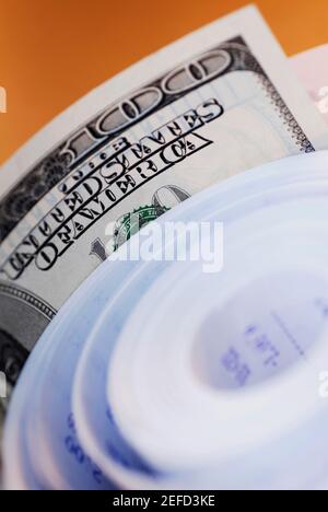 Close up of one hundred dollar bill with a roll of adding machine tape Stock Photo