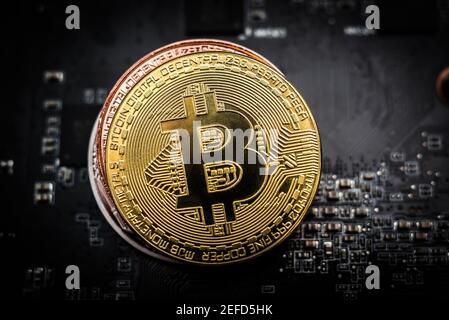 Shiny golden bitcoin on the top of a stack from bronze and silver bitcoin on computer board Stock Photo