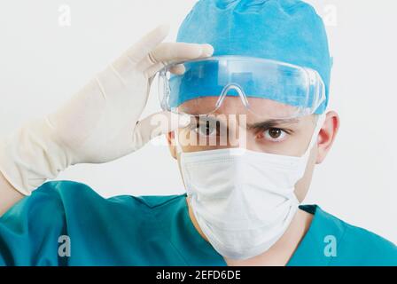 Portrait of a male doctor holding protective eyewear Stock Photo