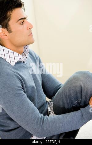 Side profile of a mid adult man sitting on the floor Stock Photo