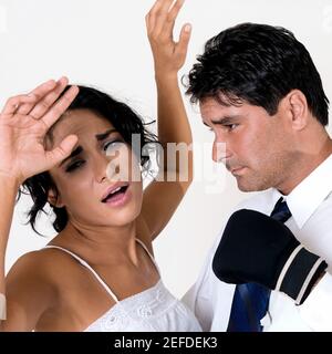 Side profile of a mid adult man wearing boxing gloves standing in front of a young woman Stock Photo