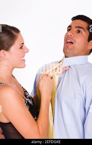 Side profile of a young woman choking a mid adult man with his tie Stock Photo