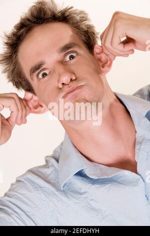 Close-up of a young man pulling his ears Stock Photo