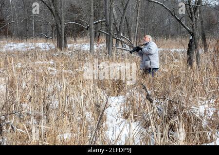 Milford, Michigan - A photographer looks for the right spot to photograph a red-tailed hawk in Kensington Metropark. Stock Photo