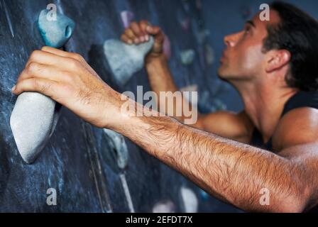 Side profile of a mid adult man climbing a wall Stock Photo
