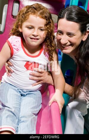 Close up of a girl on a slide held by her teacher Stock Photo