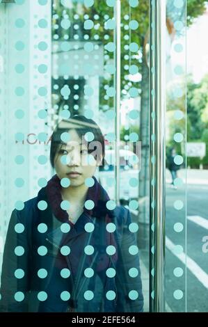 Young woman standing behind a glass door Stock Photo