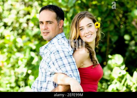 Side profile of a young woman and a mid adult man standing back to back Stock Photo
