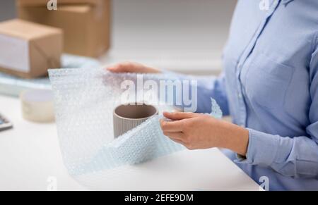 woman packing mug to parcel box at post office Stock Photo