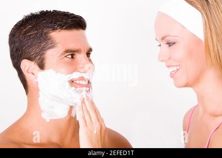 Close-up of a young woman applying shaving cream on a mid adult manÅ½s face Stock Photo