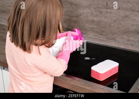 Preschool Girl make Cleaning Induction Hob. Cleaning concept Stock Photo