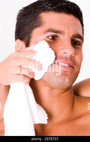 Close-up of a womanÅ½s hand wiping a mid adult manÅ½s face with a towel Stock Photo