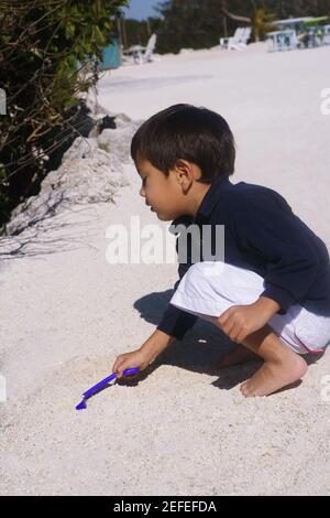 Side profile of a boy playing in sand Stock Photo