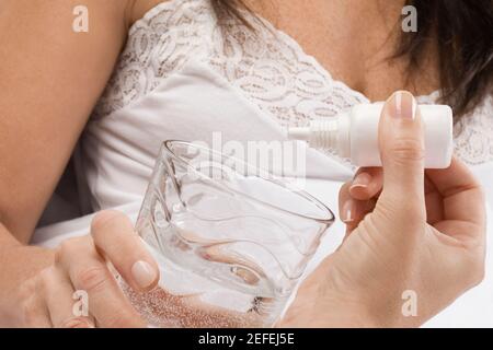 Close up of a personÅ½s hand dropping medicine into a glass of water Stock Photo