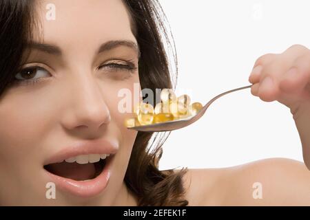Portrait of a young woman holding a spoon full of pills Stock Photo