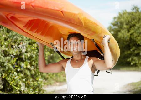 Close-up of a young man carrying a kayak on his head Stock Photo