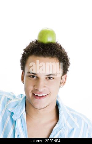 Portrait of a young man balancing a green apple on his head Stock Photo