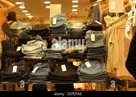 Jeans are stacked in piles at market stall. Stock Photo