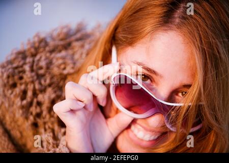 Portrait of a mid adult woman peeking over her sunglasses Stock Photo