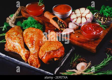 Fresh chicken legs. Raw chicken drumstick with spices and green rosemary on a black background . Raw chicken skewers on skewers.Convenience food,preco Stock Photo